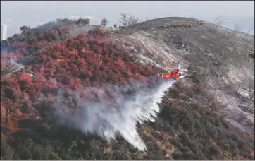  ?? The Associated Press ?? EPIC PROPORTION­S: A helicopter drops water as a wildfire called the Getty fire burns on Kenter Canyon in Los Angeles on Monday.