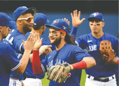  ?? DAN HAMILTON/USA TODAY SPORTS ?? Blue Jays shortstop Bo Bichette, centre, gets high fives from his teammates after leading Toronto past the visiting Tampa Bay Rays on Wednesday at the Rogers Centre. Bichette hit his 25th round tripper of the campaign and drove in five runs in a 6-3 Toronto victory.