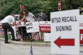  ?? AP PHOTO/MORRY GASH ?? Volunteers collect signatures to recall the entire Mequon-thiensvill­e School District board outside the Mequon Library Monday, Aug. 23, 2021, in Mequon, Wis. A loose network of conservati­ve groups with ties to major Republican donors and party-aligned think tanks is quietly lending firepower to local activists engaged in the culture war fights in schools across the country.