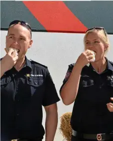  ?? Photo: Tara Miko ?? GOOD CAUSE: Firefighte­rs David McCosker and Sasha O’Keefe dig in to a Buy a Bale snag at Bunnings.