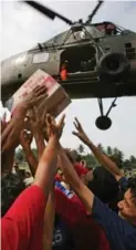  ?? DITA ALANGKARA/THE ASSOCIATED PRESS FILE PHOTO ?? Earthquake survivors reach for a box of instant noodles dropped from an Indonesian Air Force helicopter in Bantul, Indonesia, in 2006.