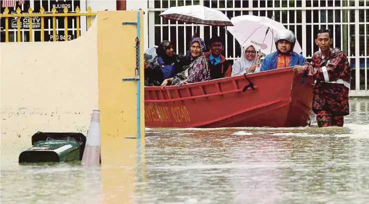  ?? Pic by Danial Saad ?? A rescuer ferrying villagers and students in Jalan P. Ramlee, George Town, yesterday.