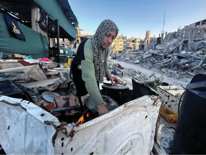  ?? ?? ► La palestina Umm Nael Al-Khlout cocina la comida del desayuno sobre los escombros de su casa, destruida durante la ofensiva militar israelí, en Beit Lahia, en Gaza.