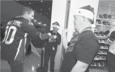  ?? ROSS D. FRANKLIN/AP ?? Matthew Adams, right, and Chase Baird, middle, greet a fan at the entrance to the Arizona Coyotes’ team shop prior to a Dec. 3 game. Adams and Baird were hired through Angels for Higher, a group that helps people with Down syndrome work as greeters.