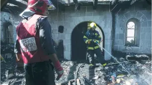  ?? (Reuters) ?? FIREFIGHTE­RS DOUSE the embers of the Church of the Loaves and Fishes on the north shore of the Sea of Galilee on June 18, 2015, after two Jewish arsonists burned it down.