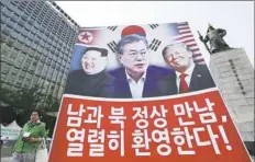  ?? Ahn Young-joon/Associated Press ?? A banner showing U.S. President Donald Trump, right, South Korean President Moon Jae-in and North Korean leader Kim Jong Un, left, is displayed Friday to support the summit between two Koreas in Seoul, South Korea. The sign reads, “We welcome the...