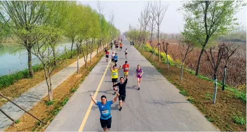  ??  ?? Corredores participan en una carrera que atraviesa una red de caminos rurales recién terminados, lo que muestra la nueva vida en el campo chino.