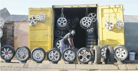  ?? Picture: Bloomberg ?? WHEELS COME OFF. A spaza shop owner stacks his goods for display on a roadside in Soweto. Spaza owners complain big retailers are killing their business ever since big malls started opening up in townships. Supermarke­ts say their advent has widened...