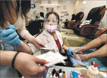  ?? Carolyn Cole Los Angeles Times ?? OWNER Crystal Trang Luong wears protective gear at Captivate Nail Spa in Fullerton. In L.A. County, a coronaviru­s hot spot, officials this week said bars, nail salons and massage parlors could resume business.