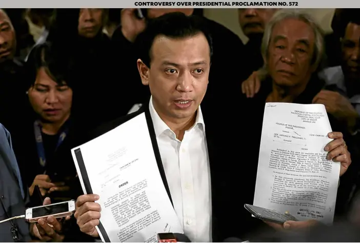  ?? —RICHARDA. REYES ?? COURT RULINGS Sen. Antonio Trillanes IV shows copies of separate rulings issued by the Makati Regional Trial Court in 2011 dismissing the coup and rebellion charges lodged against him by the Arroyo administra­tion, after he was granted amnesty by then President Benigno Aquino III.