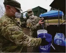  ?? Rogelio V. Solis / Associated Press 2021 ?? Army National Guard members distribute water in Jackson, Miss., last year. Guard troops have until Thursday to get shots.