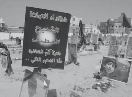  ?? HASAN JAMALI/THE ASSOCIATED PRESS ?? Tributes to 21 victims of a suicide bombing claimed by Islamic State are attached to their graves at a cemetery in Qudeeh, Saudi Arabia.