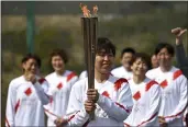  ?? PHILIP FONG, POOL — THE ASSOCIATED PRESS ?? Japanese torchbeare­r Azusa Iwashimizu, center, a member of the Japan women’s national football team, prepares to pass off the flame during the torch relay grand start outside J-Village National Training Center in Naraha, Japan, on Thursday.