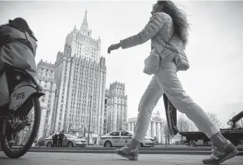  ?? ALEXANDER NEMENOV/GETTY-AFP ?? A woman walks past the Russian Foreign Ministry in Moscow. Dozens of companies and people with ties to the Kremlin were targeted Thursday by the U.S. with sanctions that included the expulsion of 10 diplomats.