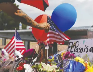  ?? CALLAGHAN O’HARE/REUTERS ?? An American flag is placed amid flowers, balloons and well-wishes in front of the Walmart store in El Paso, Texas, where a gunman opened fire targeting “Mexicans.”