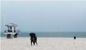  ?? JII DAIASKE/TAIPA BAY TIIES ?? A couple share an umbrella on Clearwater Beach by Pier 60 Sunday as Alberto looms in the U.S. Gulf Coast.