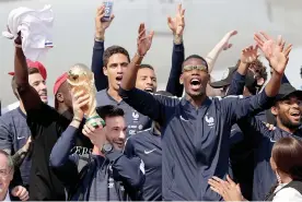  ?? — AFP ?? France goalkeeper Hugo Lloris poses with the trophy along with team mates after their arrival at the Roissy- Charles de Gaulle airport in Paris on Monday.