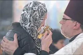  ?? Steph Chambers/Post-Gazette ?? Olga Kemaeva, wife of Anton Kemaev, kisses a cross during Anton Kemaev’s funeral service on Thursday at St. Nicholas Orthodox Church in McKees Rocks.