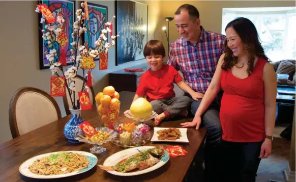  ?? JON NICHOLLS FOR THE TORONTO STAR ?? Yaz Maziar, his wife, Heslie Chua, and their son, Cameron, celebrate with traditiona­l dishes of steamed fish (for prosperity), e-fu noodles (for longevity) and sweet rice cake (also for prosperity.)