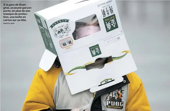  ?? PHOTO AFP ?? À la gare de Shanghai, un jeune garçon porte, en plus de son masque de protection, une boîte en carton sur sa tête.