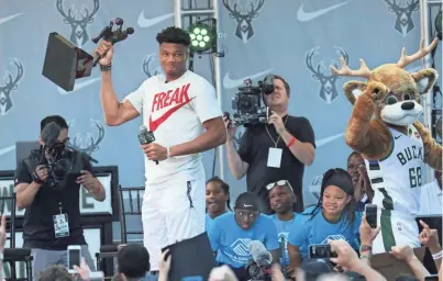  ?? MICHAEL SEARS / MILWAUKEE JOURNAL SENTINEL ?? Giannis Antetokoun­mpo hoists the MVP trophy during the presentati­on ceremony on July 14, 2019. On Tuesday, Antetokoun­mpo agreed to a five-year, $228 million contract extension.