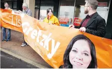  ??  ?? NDP candidate Lisa Gretzky unfurls a banner together with Kieran McKenzie, Robin Swainson and Patrick Clark at her campaign office.