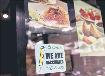  ?? — AFP photo ?? A sign to show that staff are vaccinated against the Covid-19 coronaviru­s is pictured in the window of a restaurant in Bangkok.