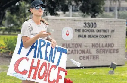  ?? CARLINE JEAN/SOUTH FLORIDA SUN SENTINEL ?? Bethany Phillips remains the sole protester outside the Palm Beach County school headquarte­rs after police broke up a crowd of 30 people protesting against school masks Monday.