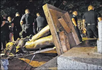  ?? Gerry Broome The Associated Press file ?? Police stand guard after the Confederat­e statue known as “Silent Sam” was toppled by protesters in August 2018 on the University of North Carolina campus in Chapel Hill, N.C. The university said this week that the monument won’t return to campus.
