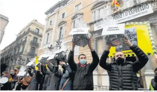  ?? MARTA PÉREZ / EFE ?? Comerciant­es sostienen el carbón que regalaron ayer a todos los consellers ante el Palau de la Generalita­t en protesta por las medidas anti Covid-19.