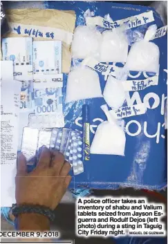  ?? MIGUEL DE GUZMAN ?? A police officer takes an inventory of shabu and Valium tablets seized from Jayson Esguerra and Rodulf Dejos (left photo) during a sting in Taguig City Friday night.