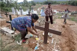  ?? AP Photo/Binsar Bakkara ?? ■ An Indonesian migrant worker places candles on the grave of her husband, who worked on a Malaysian palm oil plantation, on Dec. 9, 2018, in Sabah, Malaysia. As global demand for palm oil surges, plantation­s are struggling to find enough laborers, frequently relying on brokers who prey on the most at-risk people. The bodies of migrants who die are sometimes not sent home.