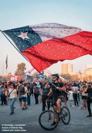  ?? R M NUNES/SHUTTERSTO­CK ?? In Santiago, a protester waves a Chilean flag riddled with bullet holes