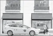  ?? RON ANTONELLI/BLOOMBERG NEWS ?? A taxi cab drives past pedestrian­s in front of a Barneys New York Inc. store on Madison Avenue in New York. In March, Barneys rolled out a new website in which nearly every page features personaliz­ed content. “For 1 million users, we want to have 1...