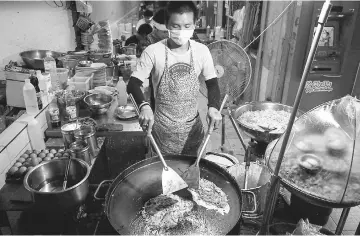  ??  ?? A man cooking food at a street stall in the Phrakanong district of Bangkok. — AFP photo