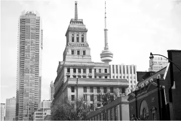  ??  ?? The Canada Life building (center) stands in front of the CN Tower (right), in the financial district of Toronto, on July 7, 2016. — WPBloombeg photo