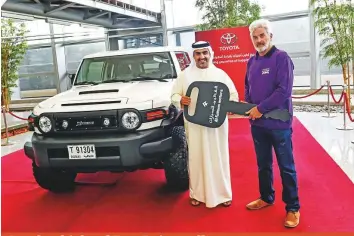  ?? Virendra Saklani/Gulf News ?? Ahmad Ali Mohammad, marketing operations manager of Toyota Al Futtaim, the main sponsor of the Gulf News Overnighte­r Fun Drive, presents the keys to the lead vehicle, a FJ Cruiser Xtreme, to route director John Spiller.