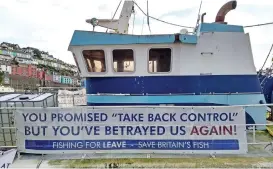  ?? (AFP) ?? A ‘Fishing For Leave’ campaign group’s sign about Brexit on a boat in the harbour in Brixham, on Thursday