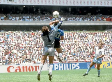  ?? GETTY IMAGES ?? In perhaps the most controvers­ial goal in football history, Diego Maradona uses his hand to punch the ball into the net beyond England goalkeeper Peter Shilton for Argentina’s first goal in their 2-1 win in the 1986 World Cup quarterfin­al.