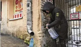  ?? JOHN LEICESTER/AP ?? Kateryna Luchkina, a 31-year-old worker at Kyiv’s Department of Health, collects rainwater from a drainpipe in Kyiv, Ukraine, on Thursday. Residents of Ukraine’s bombed but not cowed capital roamed the streets in search of water.