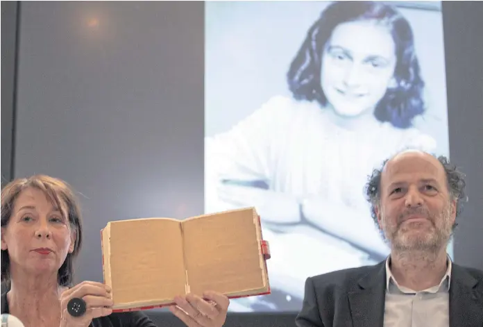  ??  ?? READING INTO IT: Teresien da Silva and Ronald Leopold of the Anne Frank Foundation show a facsimile of Anne Frank’s diary with two pages taped off during a conference in Amsterdam, Netherland­s.