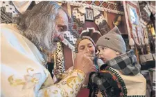  ?? PAULA BRONSTEIN GETTY IMAGES ?? A priest gives Holy Communion to a child Sunday during Easter service at the Church of the Nativity of the Theotokos in Kryvorivni­a, western Ukraine.