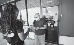  ?? GERALD HERBERT/AP ?? Dazmine Allen, left, gives store owner Kenneth McGruder some virus info in New Orleans.