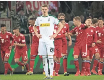  ?? FOTO: DPA ?? Sinnbild des Samstags im Borussia-park: Mönchengla­dbachs Matthias Ginter steht ratlos auf dem Platz, während die Bayern das Tor zum 3:1 feiern.