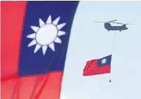  ?? CHIANG YING-YING THE ASSOCIATED PRESS ?? A military helicopter carries the Taiwan national flag Sunday as it flies over the Presidenti­al Building in Taipei, Taiwan, during the island’s National Day celebratio­ns.