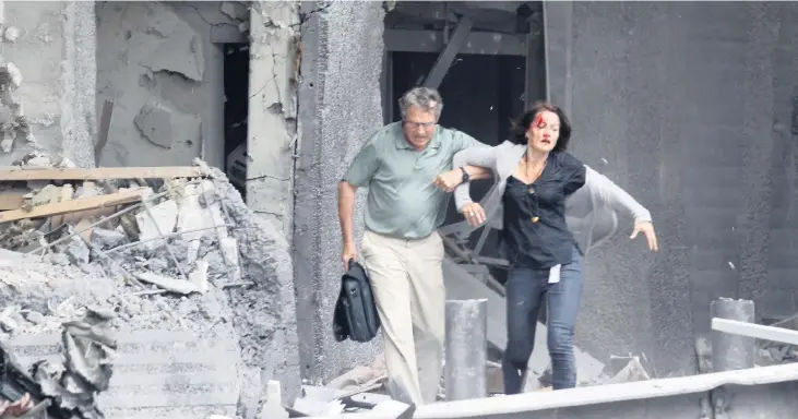  ?? Bild: Morten Holm ?? En skadad kvinna får hjälp ut ur en byggnad av sin kollega i regeringsk­varteret efter explosione­n.