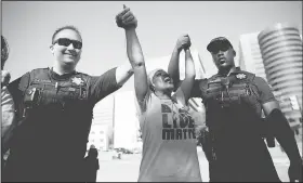  ?? AP/Tulsa World/MIKE SIMONS ?? Angie Pitts, of Tulsa, holds hands with Tulsa Police officers Thursday while protesting the death of Terence Crutcher, who was shot by police, in front of the Tulsa Country Courthouse, in Tulsa, Okla.