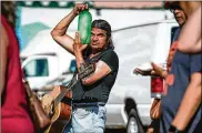  ?? KC MCGINNIS / THE NEW YORK TIMES ?? Randy Kong cools off with a bottle of ice while performing at the Des Moines Farmers Market in Iowa on Saturday.