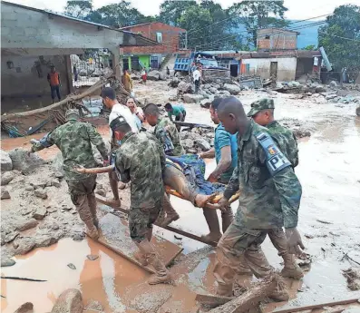  ?? COLOMBIAN ARMY PHOTO VIA AP ?? Soldiers carry a victim on a stretcher Saturday in Mocoa, Colombia, after an avalanche of water from a river overflowin­g amid intense rains swept through the city as people slept.