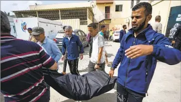  ?? Abdel Kareem Hana Associated Press ?? BODIES of Palestinia­ns are carried into a hospital Saturday in Deir al Balah in the central Gaza Strip following an Israeli airstrike in Nuseirat that killed five. Separate airstrikes in Rafah killed more than a dozen.